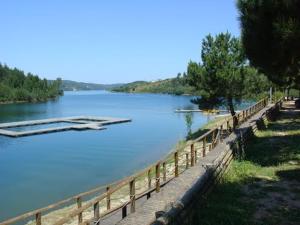 een rivier met een houten hek en een boot in het water bij Quinta da Eira Velha in Aldeia do Mato