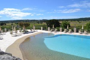 a large swimming pool with chairs and umbrellas at Masseria Torricella in Alberobello