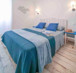 een slaapkamer met een bed met blauwe lakens en blauwe kussens bij Faro di Capo Testa in Bonifacio