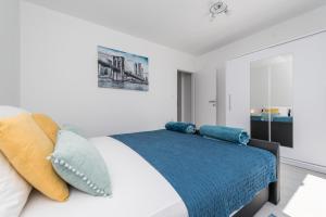 um quarto branco com uma cama com almofadas em Apartments HIPERION em Zadar