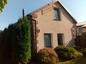 une maison avec un grand bush devant elle dans l'établissement Domek nad Kanałem Łuczańskim, à Giżycko