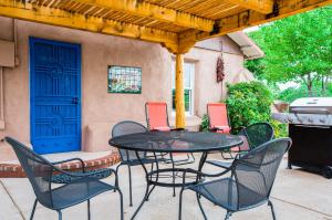 een patio met een tafel en stoelen en een blauwe deur bij Casa La Huerta in Albuquerque