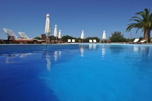 a large blue swimming pool with chairs and umbrellas at Eri Hotel in Parikia