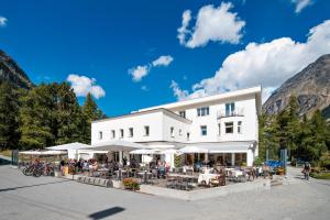 un edificio blanco con mesas y sombrillas blancas en Hotel Morteratsch, en Pontresina