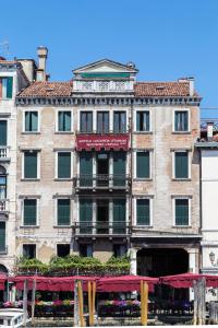 Um edifício antigo com um toldo vermelho à frente. em Antica Locanda Sturion Residenza d'Epoca em Veneza