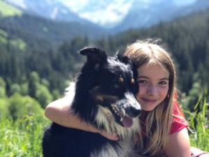 Una ragazza che tiene in braccio un cane bianco e nero di Family Retreat Maria Alm a Maria Alm am Steinernen Meer