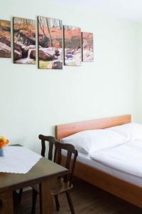 a bed and a table in a room with four paintings at Vila Sofia in Luhačovice