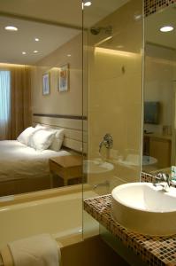 a bathroom with a shower and a sink and a bed at Grandview Hotel Macau in Macau