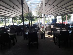 un comedor con mesas y sillas y muchas ventanas en Hotel Restaurant Hellas, en Gelting