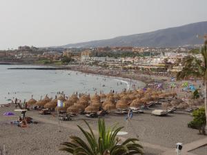 una spiaggia con un mucchio di ombrelloni e una folla di persone di Orlando Apart ad Adeje