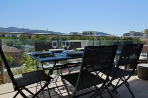 a table with two chairs and wine glasses on a balcony at Appartement plage Salata Rosas in Roses