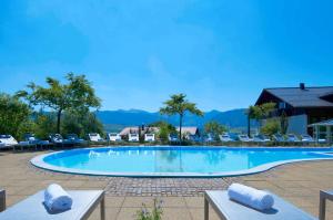 uma grande piscina com cadeiras e montanhas ao fundo em Allgäu Sonne em Oberstaufen