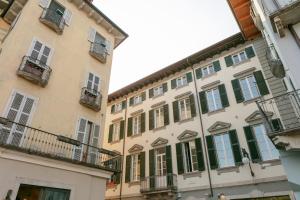 Verbania - Luxury Italy Apartments في فيربانيا: مبنى طويل وبه نوافذ خضراء مغلقة وشرفات