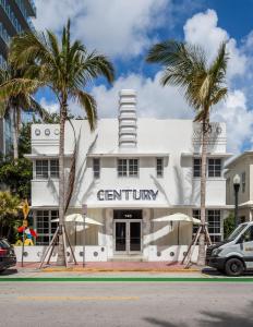 a white building with palm trees in front of it at Century Hotel in Miami Beach