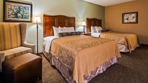 Best Western Plus Country Cupboard Inn في لويسبرغ: غرفة فندقية بسريرين وكرسي