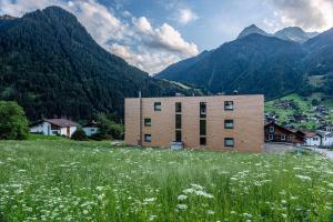 budynek na wzgórzu z polem kwiatów w obiekcie Appartements Ausblick w mieście St. Gallenkirch