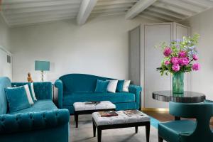 una sala de estar con muebles azules y un jarrón de flores en San Firenze Suites & Spa, en Florencia