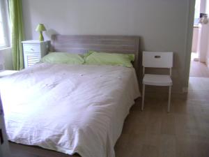 1 dormitorio con 1 cama blanca y 1 silla en le corsaire, en Granville