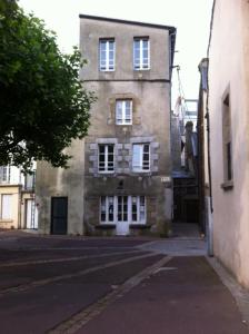 un antiguo edificio de ladrillo con ventanas blancas en una calle en le corsaire, en Granville