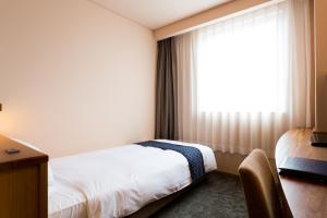 una camera d'albergo con letto e finestra di Takanokono Hotel a Matsuyama