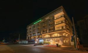 um edifício com um sinal verde no lado em White Lotus Hotel em Udupi