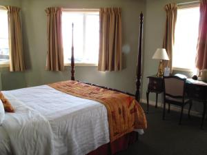 um quarto com uma cama, uma secretária e janelas em Brigantine Inn em Lunenburg