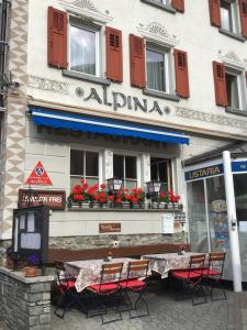 a restaurant with tables and chairs in front of a building at Hotel Alpina in Zernez