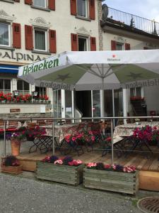 a patio with tables and chairs and an umbrella at Hotel Alpina in Zernez