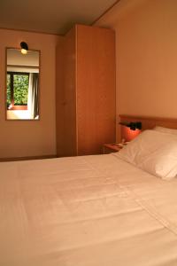 1 dormitorio con cama blanca y ventana en Hotel Les Jumeaux Courmayeur, en Courmayeur