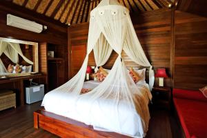 1 dormitorio con 1 cama con mosquitera en Dream Beach Cottages, en Nusa Lembongan