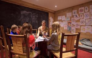 een groep kinderen die rond een tafel in een kamer zitten bij Chalet-Hôtel La Marmotte, La Tapiaz & SPA, The Originals Relais in Les Gets