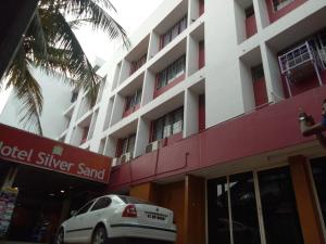 um carro branco estacionado em frente a um edifício em Hotel Silver Sand em Trivandrum