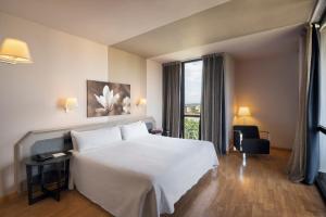 Habitación de hotel con cama blanca y ventana en Ciutat de Granollers, en Granollers