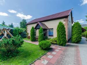 une maison avec des arbres et des buissons devant elle dans l'établissement Domek nad Kanałem Łuczańskim, à Giżycko