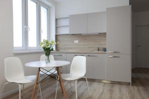 eine Küche mit weißen Stühlen und einem Tisch mit einer Blumenvase in der Unterkunft City Center Best Place Apartments in Bratislava