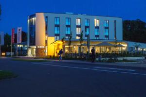 duas pessoas andando em frente a um prédio à noite em Hotel Susato em Soest