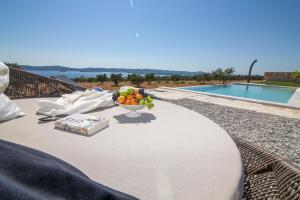 uma mesa com uma tigela de fruta ao lado de uma piscina em Estate Villa Duo em Biograd na Moru