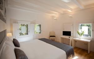 a bedroom with a bed and a desk and a television at Hotel Sitges in Sitges