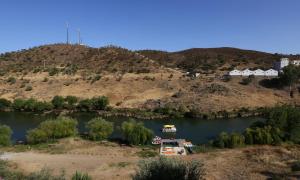 un bateau dans une rivière avec une colline en arrière-plan dans l'établissement Mértola low-cost, à Mértola