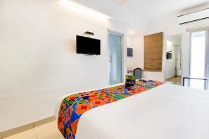 um quarto com uma cama branca e um cobertor estampado colorido em FabExpress Kalyan - Nr Dairy Dan Circle em Vadodara