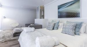 - une chambre avec un grand lit blanc et des oreillers bleus dans l'établissement Swakopmund Luxury Suites, à Swakopmund