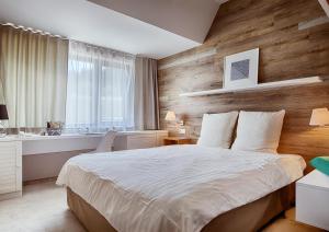 um quarto com uma cama grande e uma parede de madeira em Cihelny Golf & Wellness Resort em Karlovy Vary