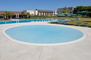 einen großen blauen Pool mit Stühlen und Sonnenschirmen in der Unterkunft Villa Quaranta Tommasi Wine Hotel & SPA in Pescantina