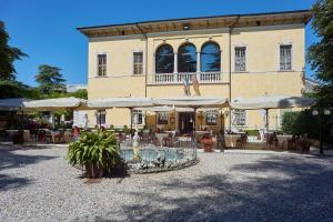 ein Gebäude mit einem Brunnen und Sonnenschirmen davor in der Unterkunft Villa Quaranta Tommasi Wine Hotel & SPA in Pescantina