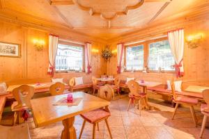 un restaurante con mesas y sillas de madera y ventanas en Hotel Garni la Stua, en Selva di Cadore