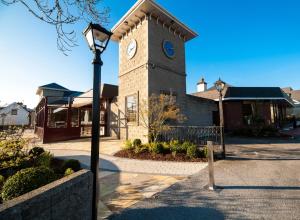 una torre dell'orologio di fronte a un edificio con un lampione di Treacys West County Conference and Leisure Centre a Ennis