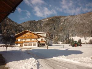 una casa nella neve con un trattore davanti di Pension Wiesenhof a Campo di Trens