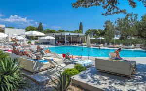 um grupo de pessoas sentadas em espreguiçadeiras à beira de uma piscina em Pharos Hvar Hotel em Hvar