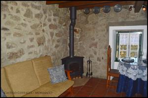 uma sala de estar com um fogão a lenha e um sofá em Castelo Cottages II em Monsanto