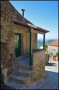 um edifício de pedra com uma porta verde e escadas em Castelo Cottages II em Monsanto